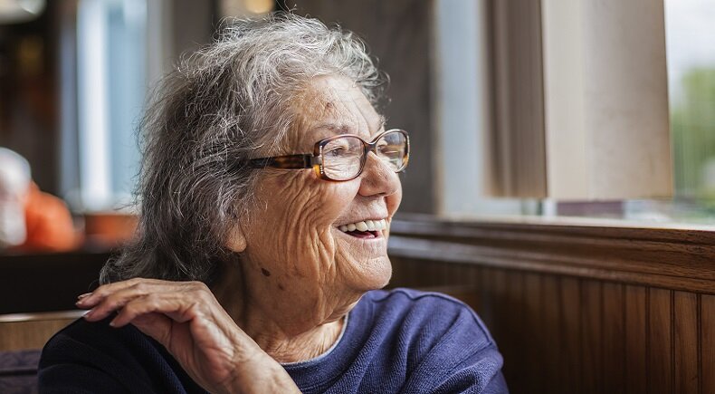 An elderly woman with dementia and sight loss smiling